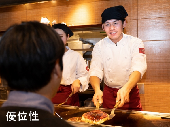 千房でお好み焼きをお客様に提供するスタッフ写真